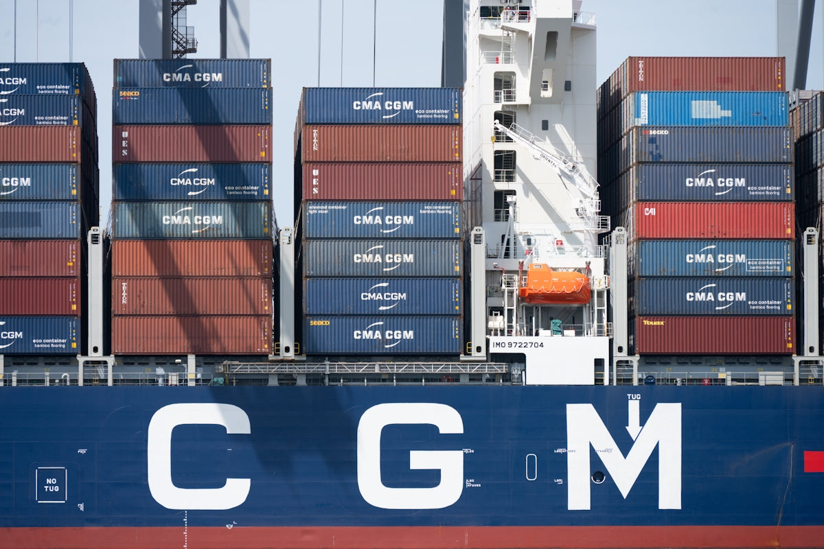 Cargo ship with stacked containers and c g m branding.
